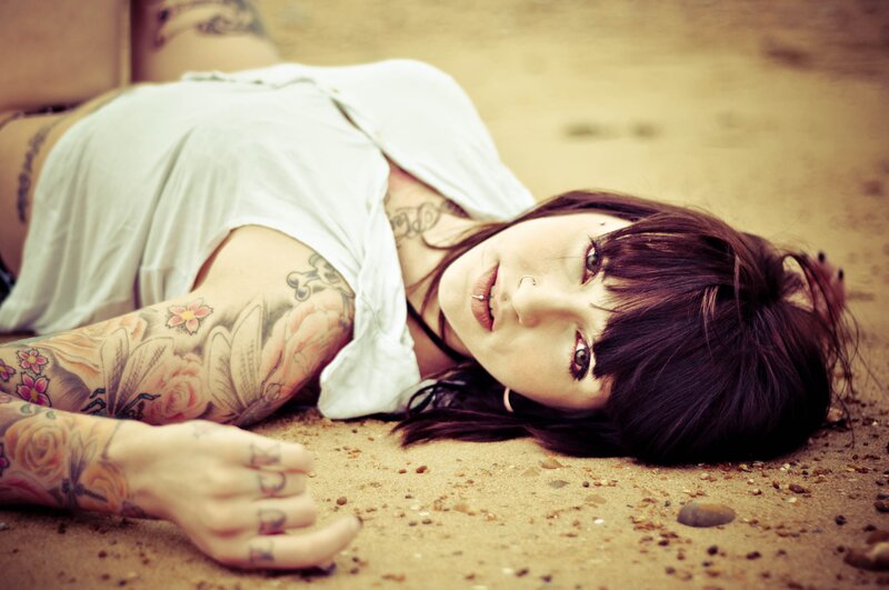 woman with tattoos lying on sand