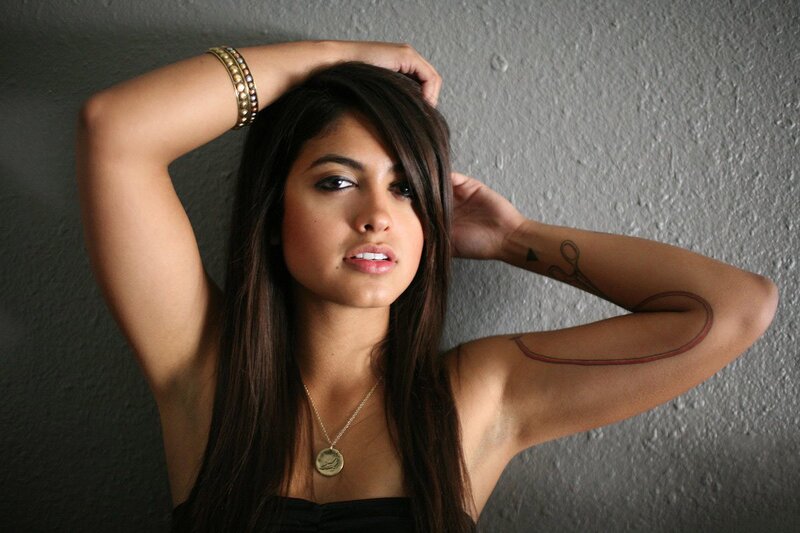 woman with tattoos posing against wall