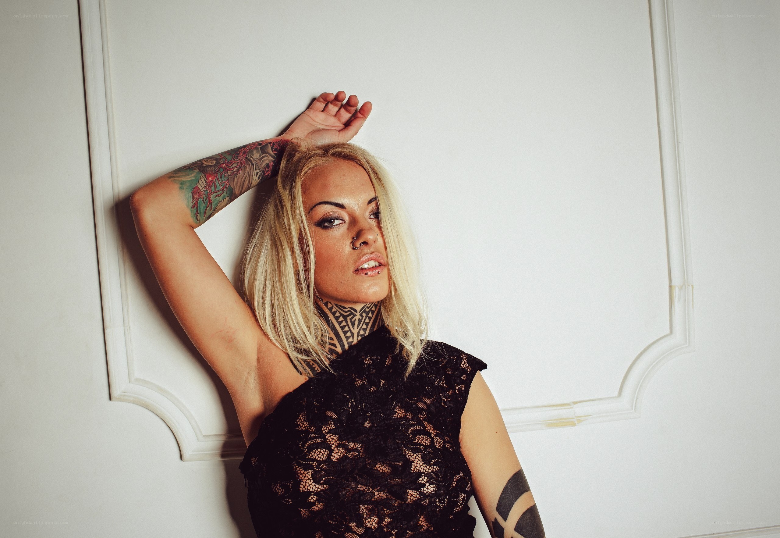 woman with tattoos posing against wall