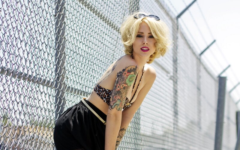 woman with tattoos posing by fence