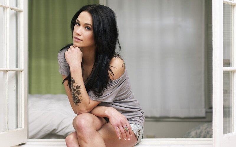 woman with tattoos sitting by window