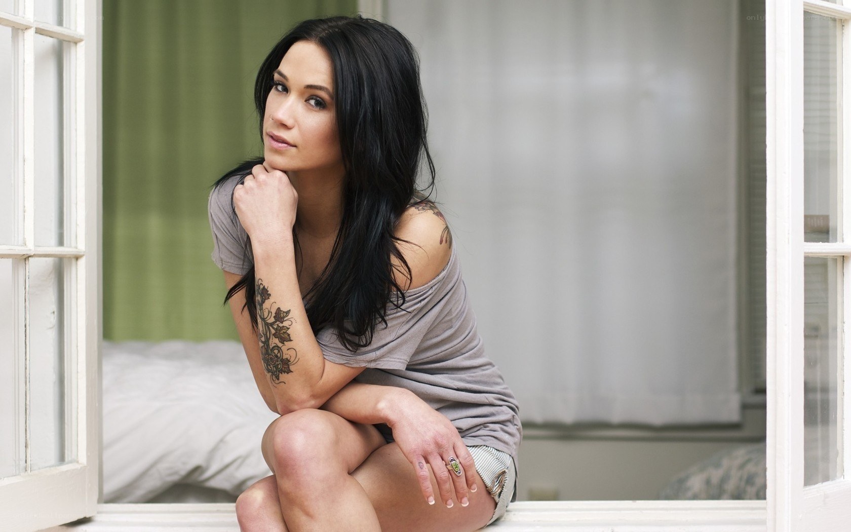 woman with tattoos sitting by window
