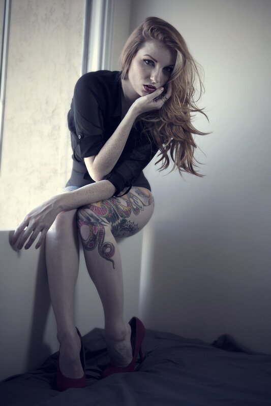 woman with tattoos sitting by window