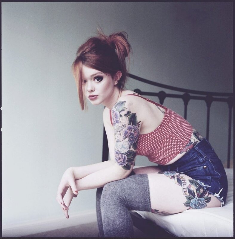 woman with tattoos sitting on bed