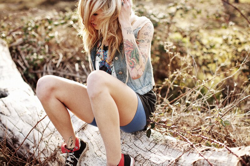 woman with tattoos sitting on log