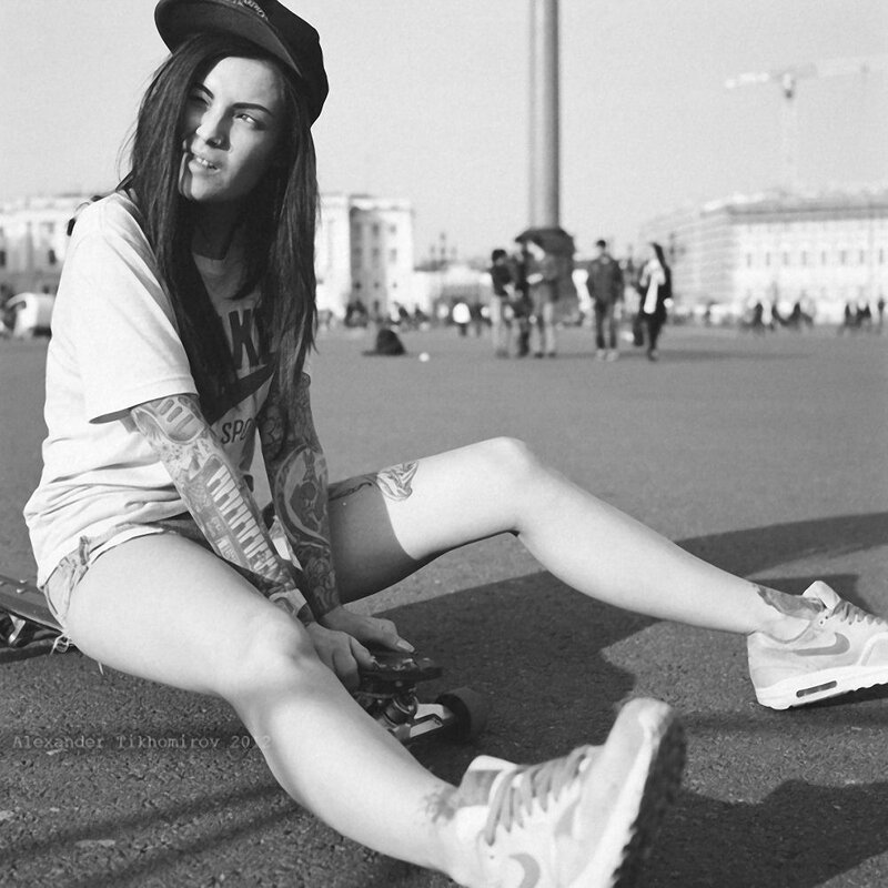 woman with tattoos sitting on skateboard