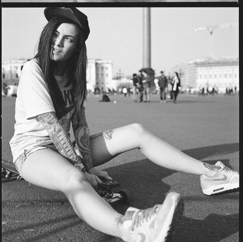 woman with tattoos sitting on skateboard