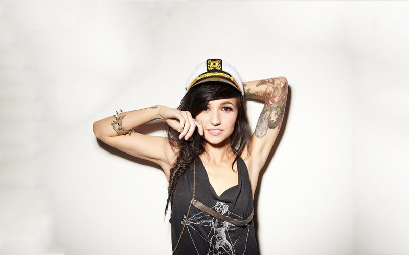 woman with tattoos wearing captain's hat