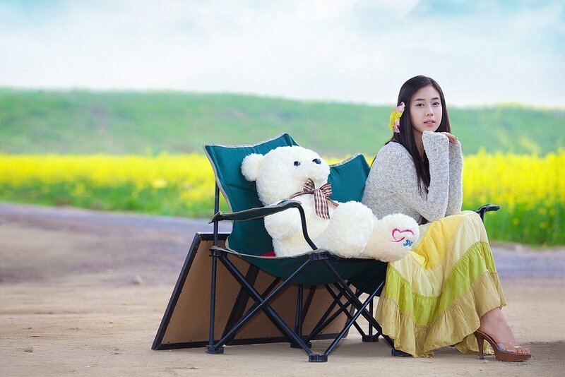 Woman with teddy bear in field