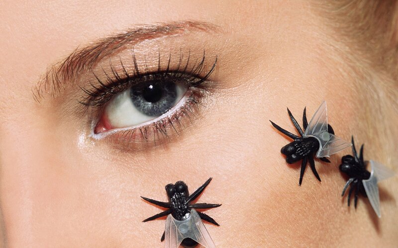 woman with toy spiders on face