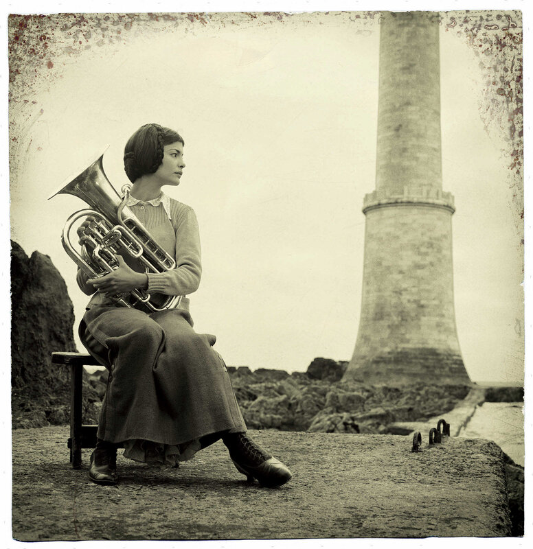 Woman with tuba by lighthouse