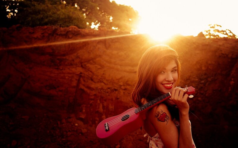 Woman with ukulele at sunset