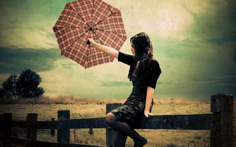 Woman with umbrella in field