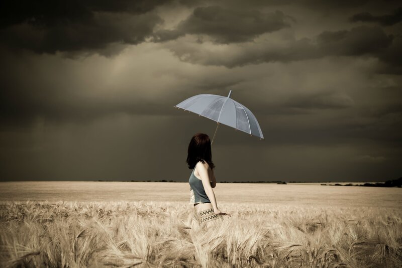 Woman with umbrella in wheat field