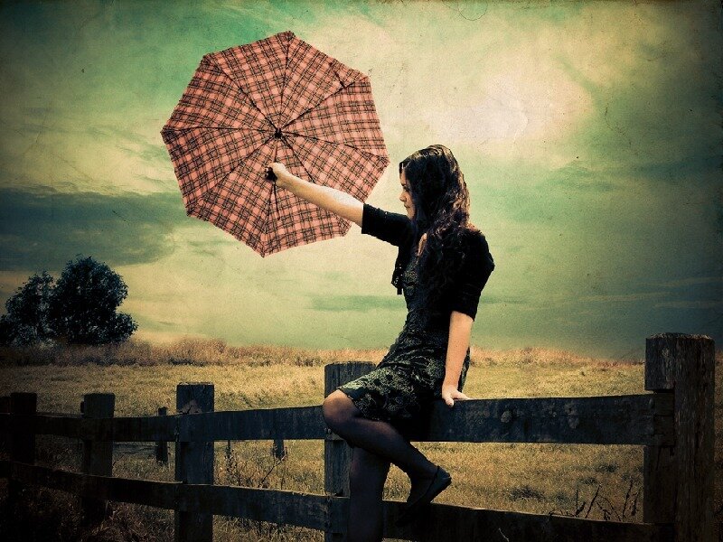 Woman with umbrella on fence