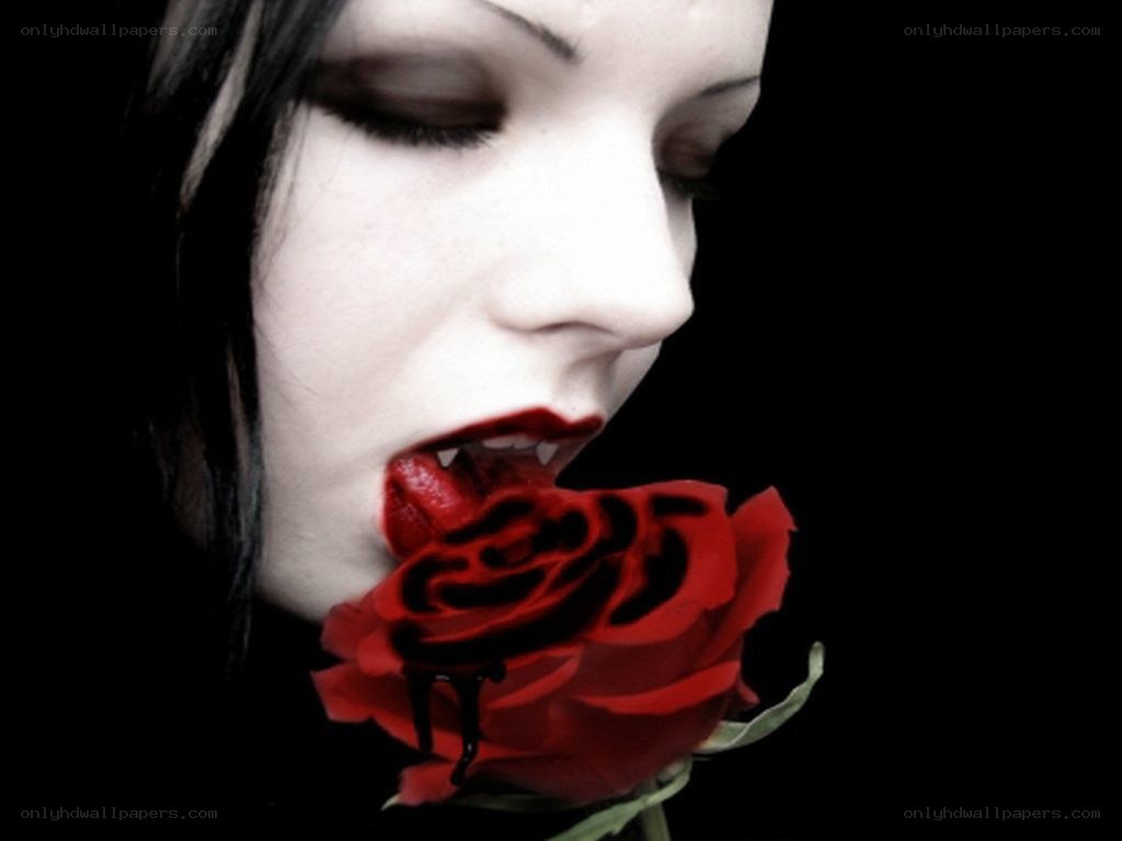 woman with vampire makeup biting rose