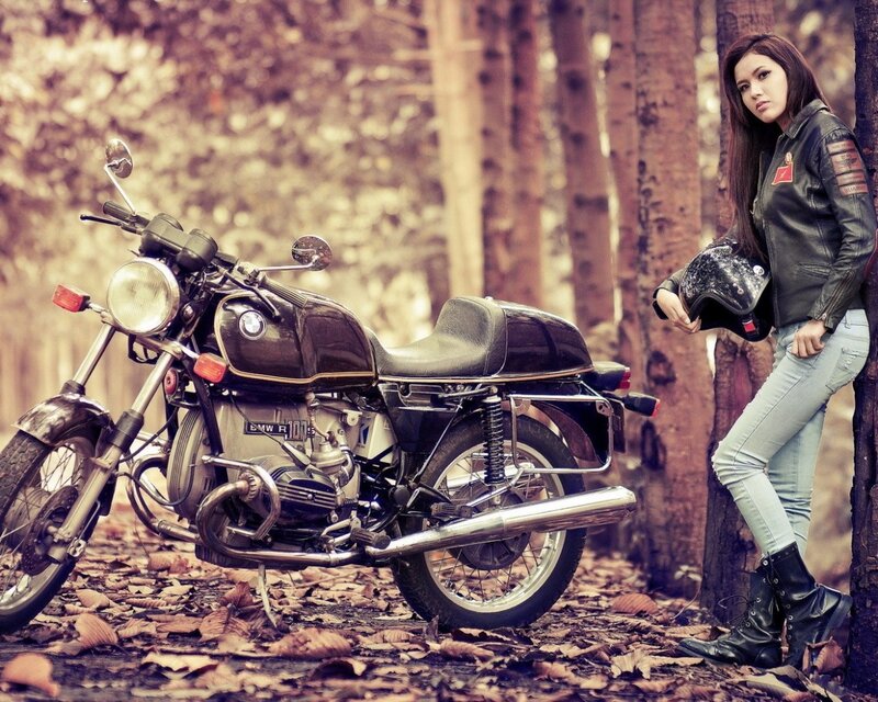 Woman with vintage motorcycle in forest