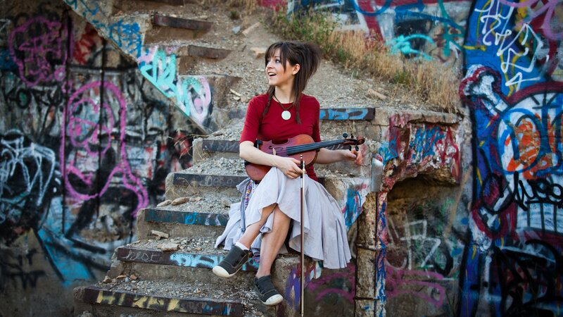 Woman with violin on graffiti stairs