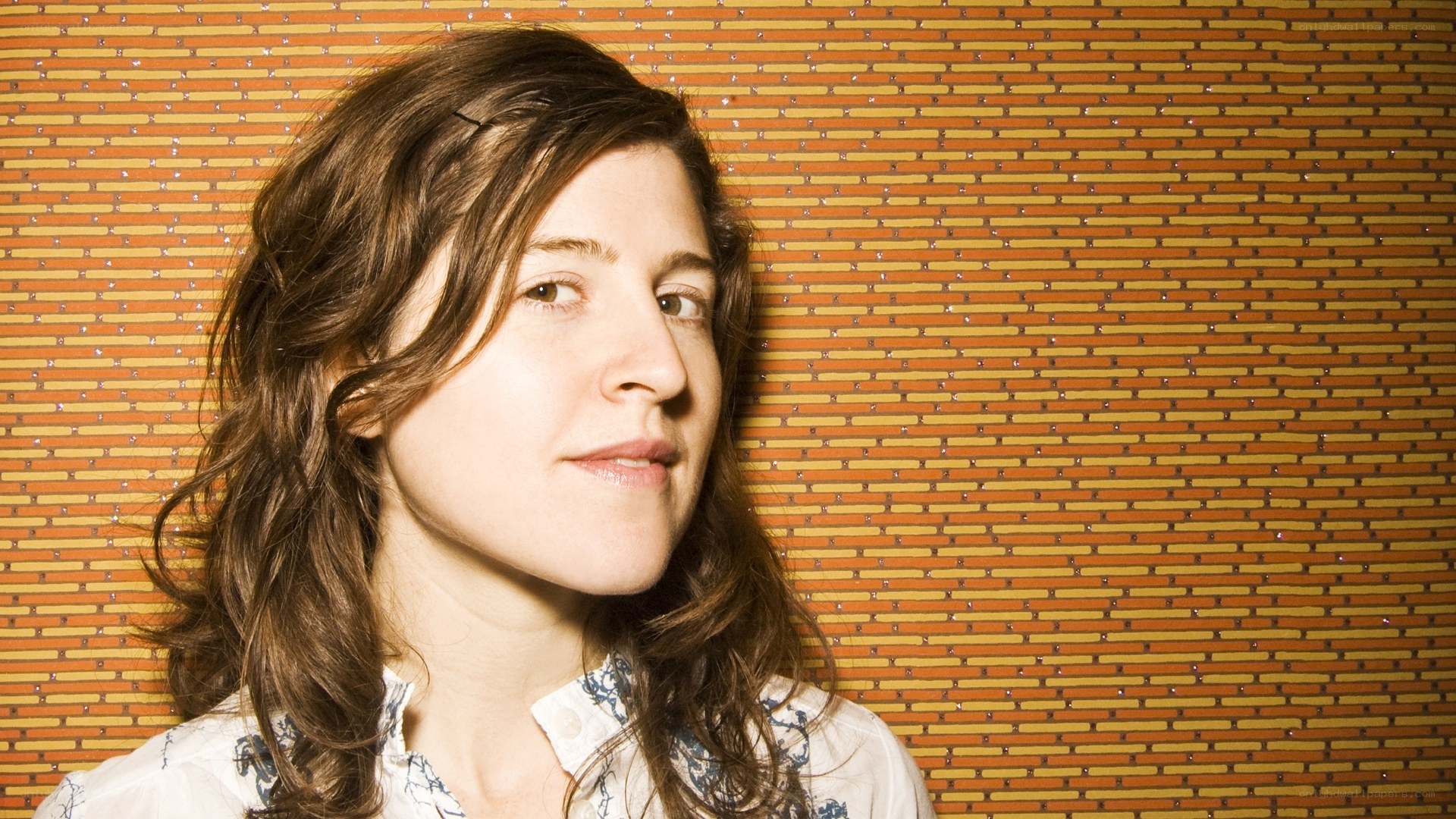 woman with wavy hair against textured wall