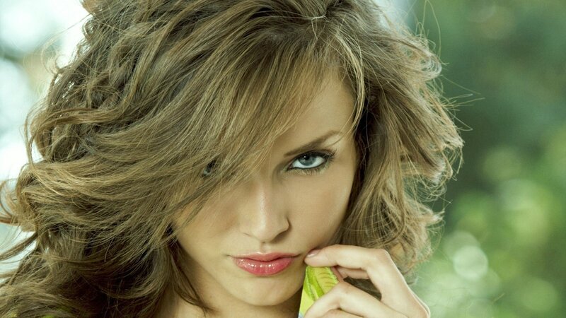 woman with wavy hair holding leaf