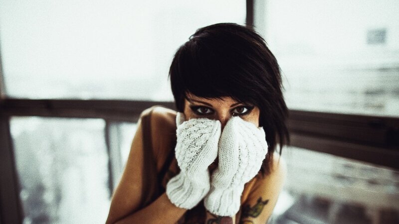 woman with white gloves covering face