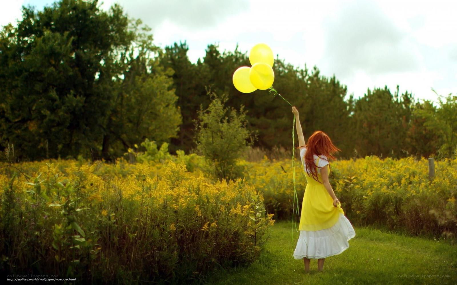 Woman with yellow balloons in field