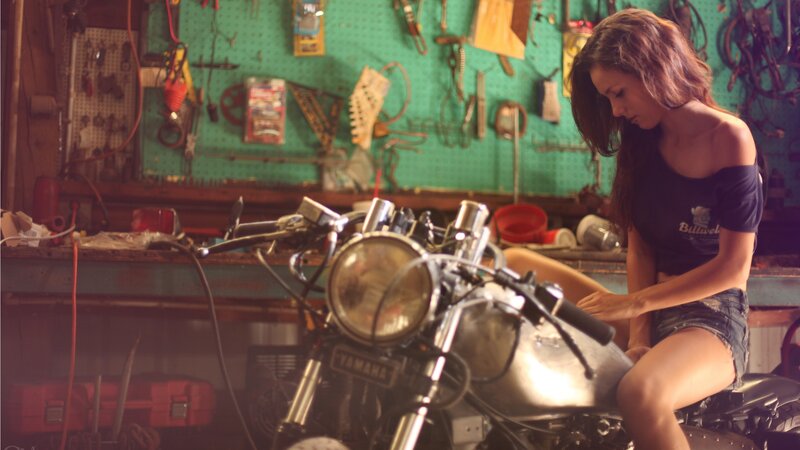 woman working on motorcycle in garage