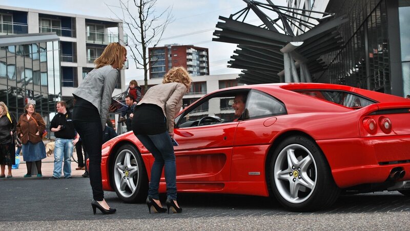 Women admiring a red Ferrari