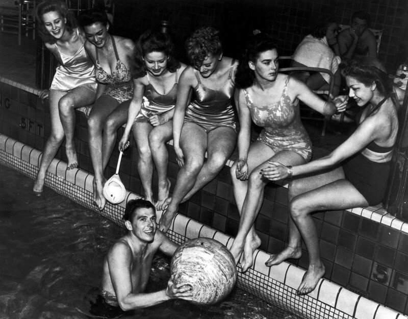 Women at poolside with man in water