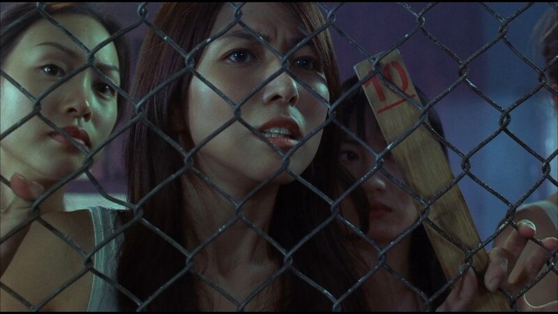 women behind a chain-link fence