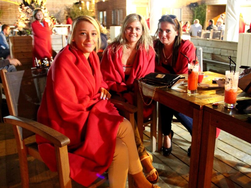 Women in red blankets at outdoor bar