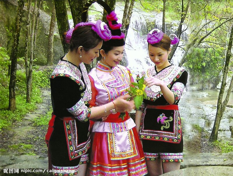 Women in traditional attire by a waterfall