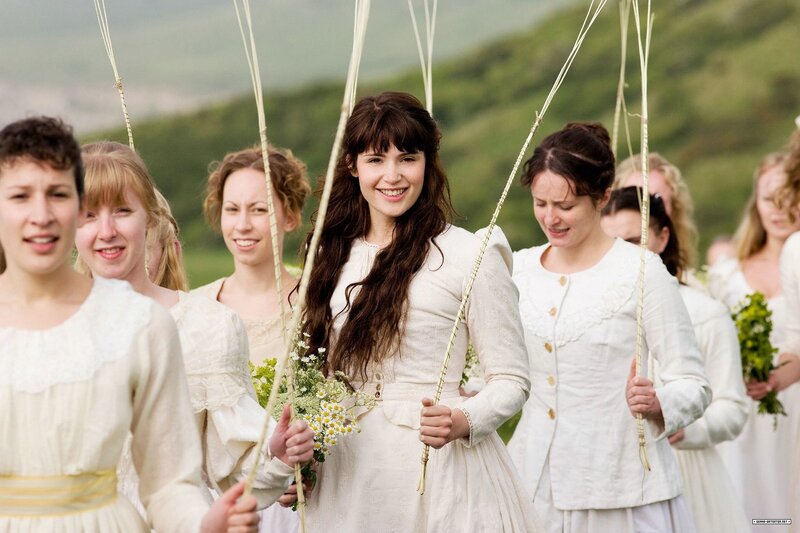 Women in white dresses holding sticks