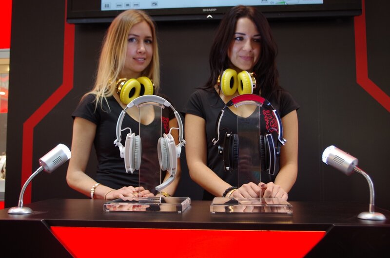 Women presenting headphones at a booth
