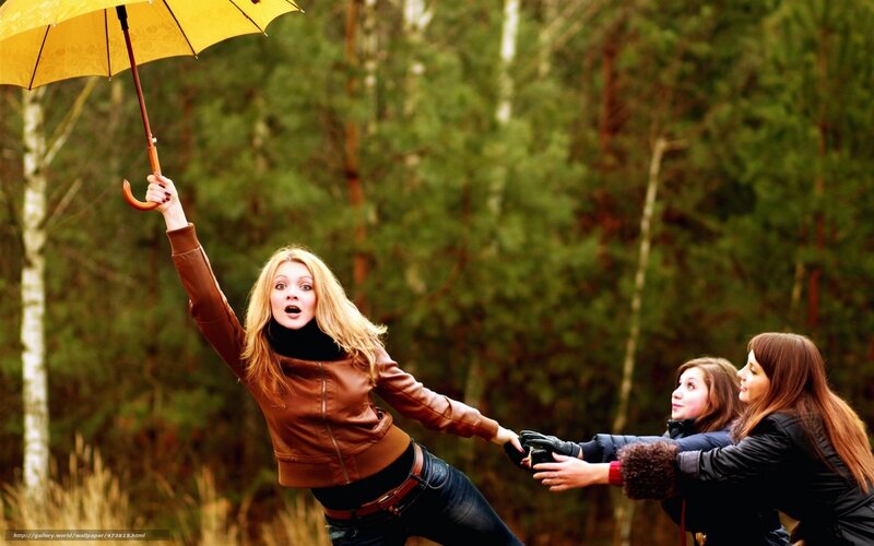 Women pulling woman with umbrella