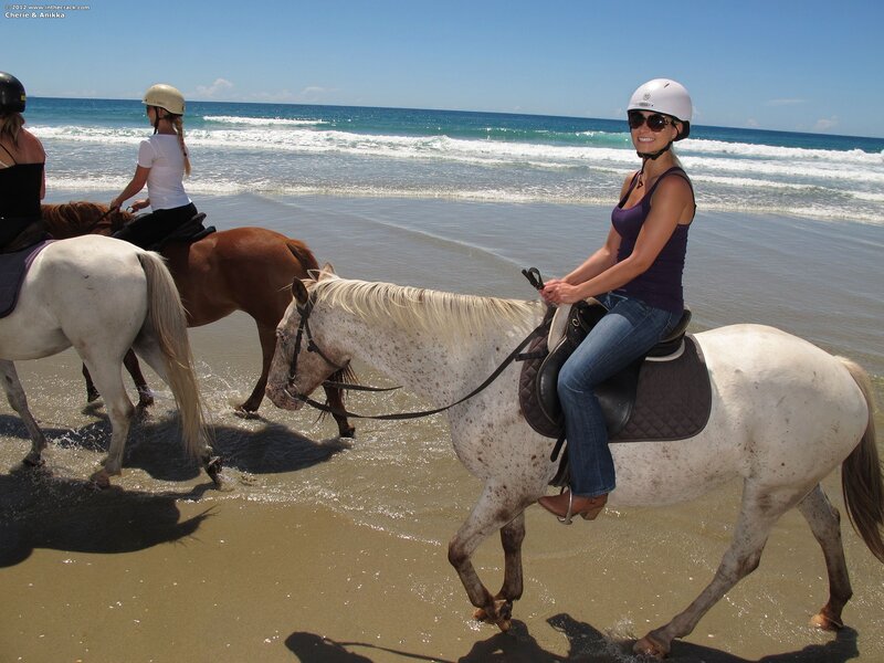 Women riding horses on the beach