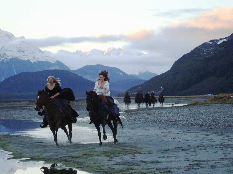 Women riding horses through a river