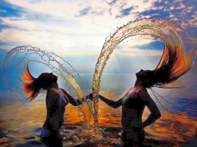 Women splashing water at sunset