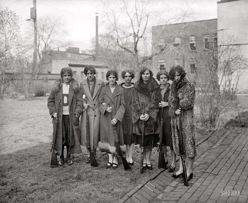 Women with rifles in a yard