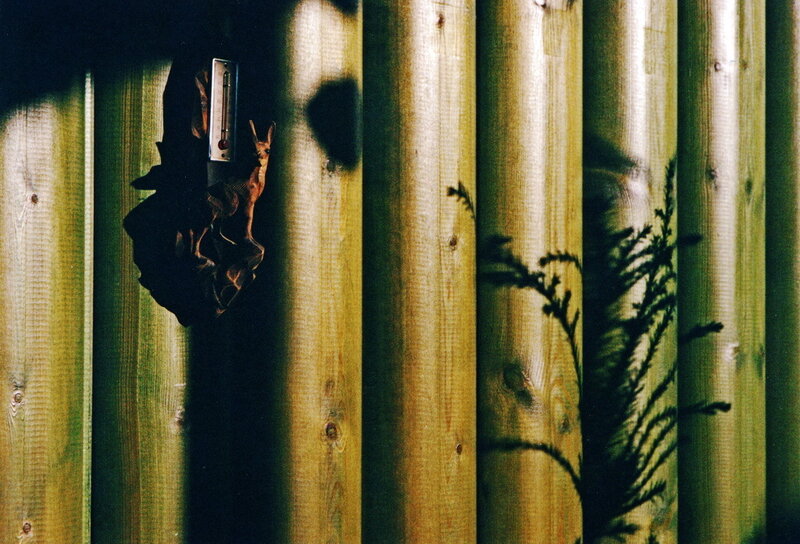 Wood fence with thermometer and shadows