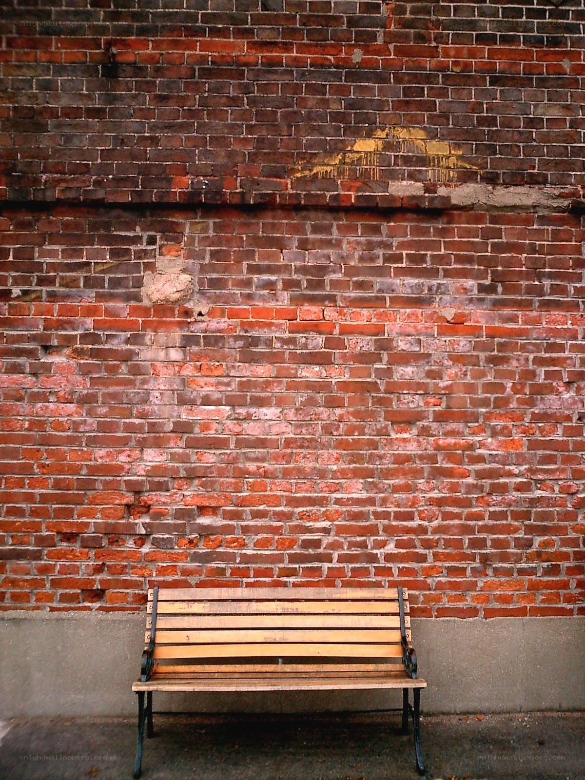 Wooden bench against brick wall