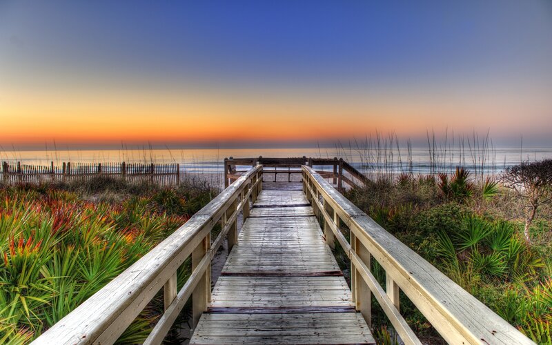 Wooden boardwalk to the beach at sunset