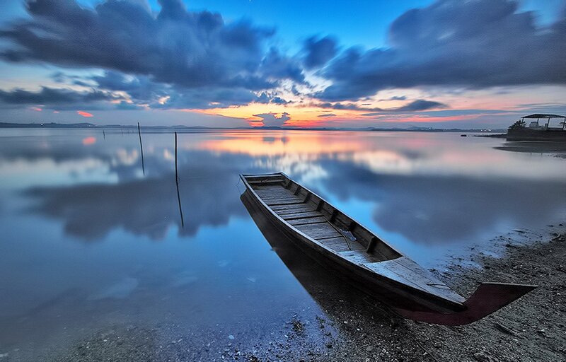 Wooden Boat on Shore — Blue, Serene, Sunset, Photograph, Water