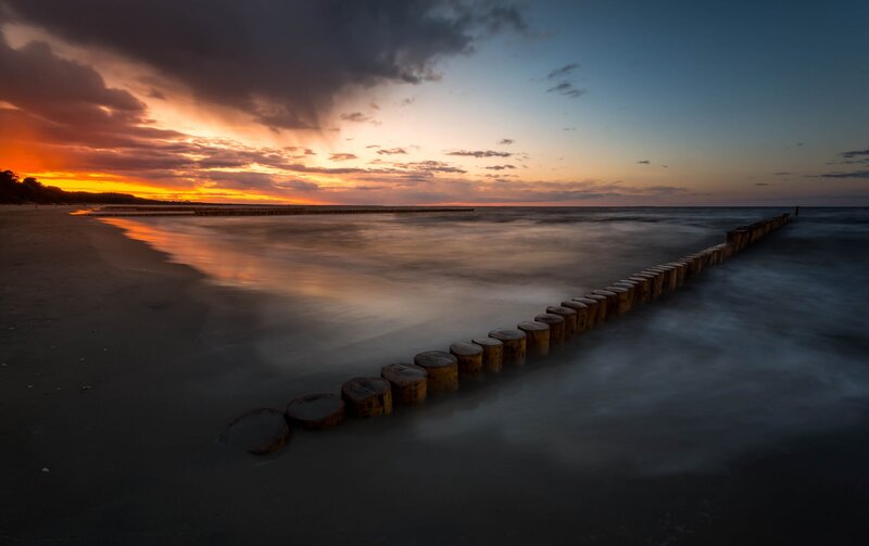Wooden Breakwater at Sunset — Orange, Dramatic, Photograph