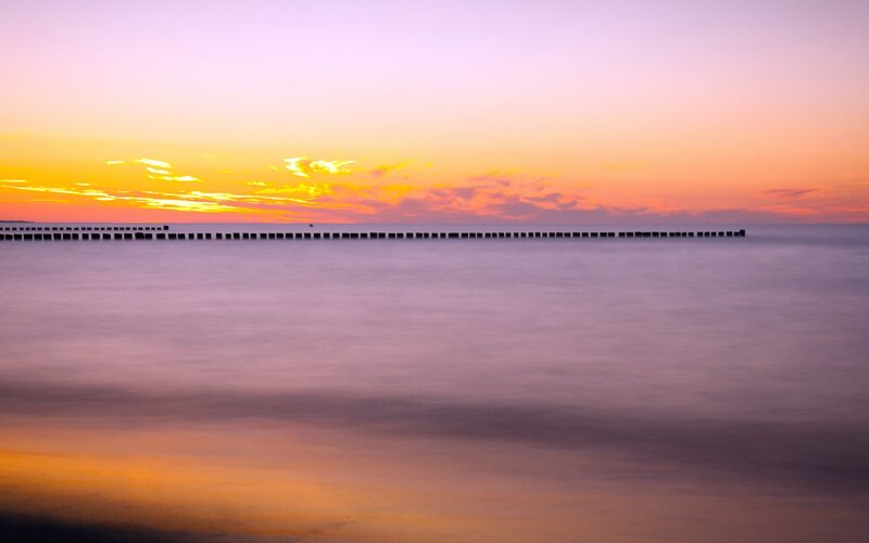 Wooden Breakwater at Sunset — Orange, Serene, Photograph