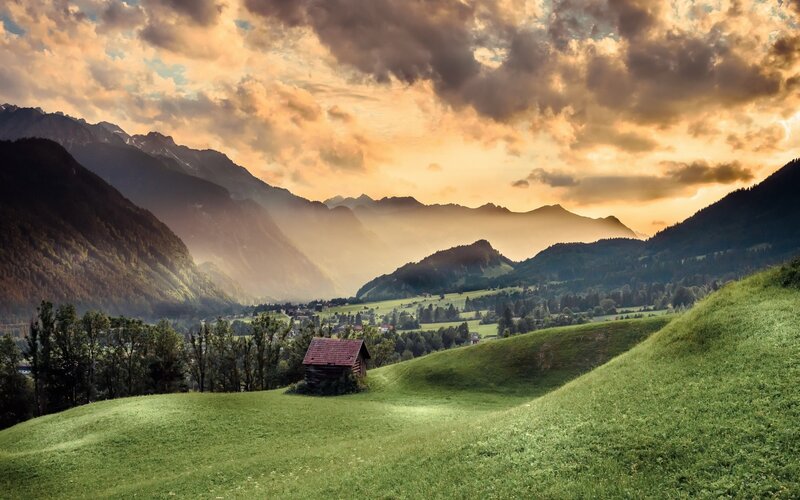 Wooden Cabin in Valley — Green, Serene, Sunset, Photograph, Mountains, Clouds