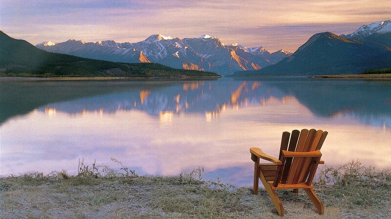 Wooden chair by a lake at sunset