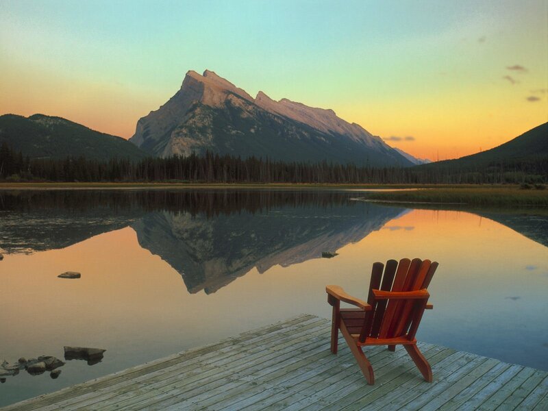 Wooden chair by a lake at sunset
