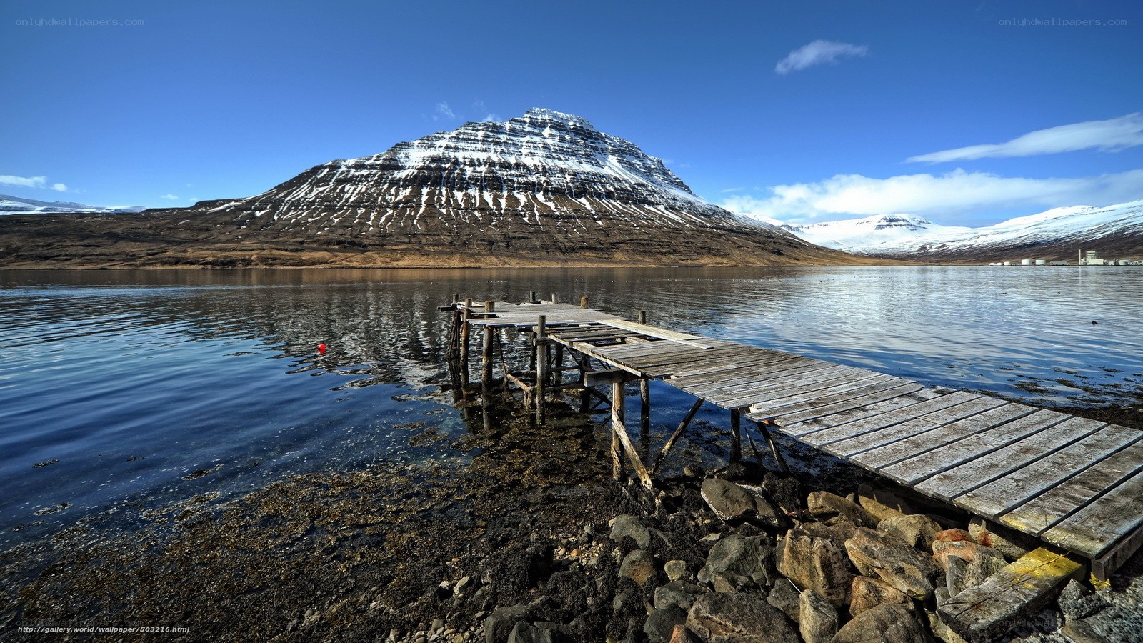Wooden dock by snowy mountain