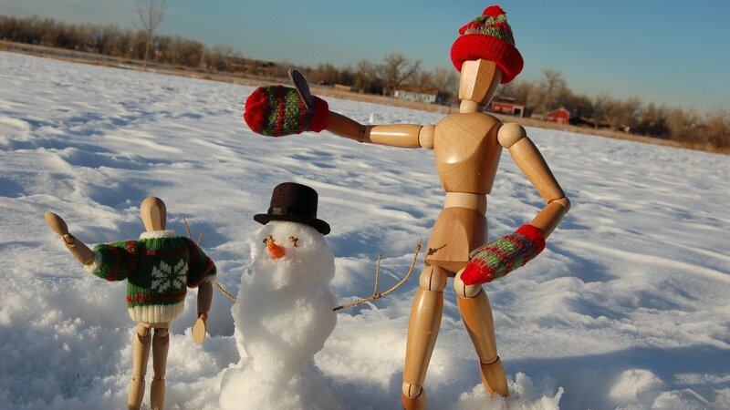 Wooden figures with snowman in snow